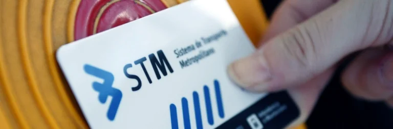 A hand presents an STM transit card to a circular red contactless validator.